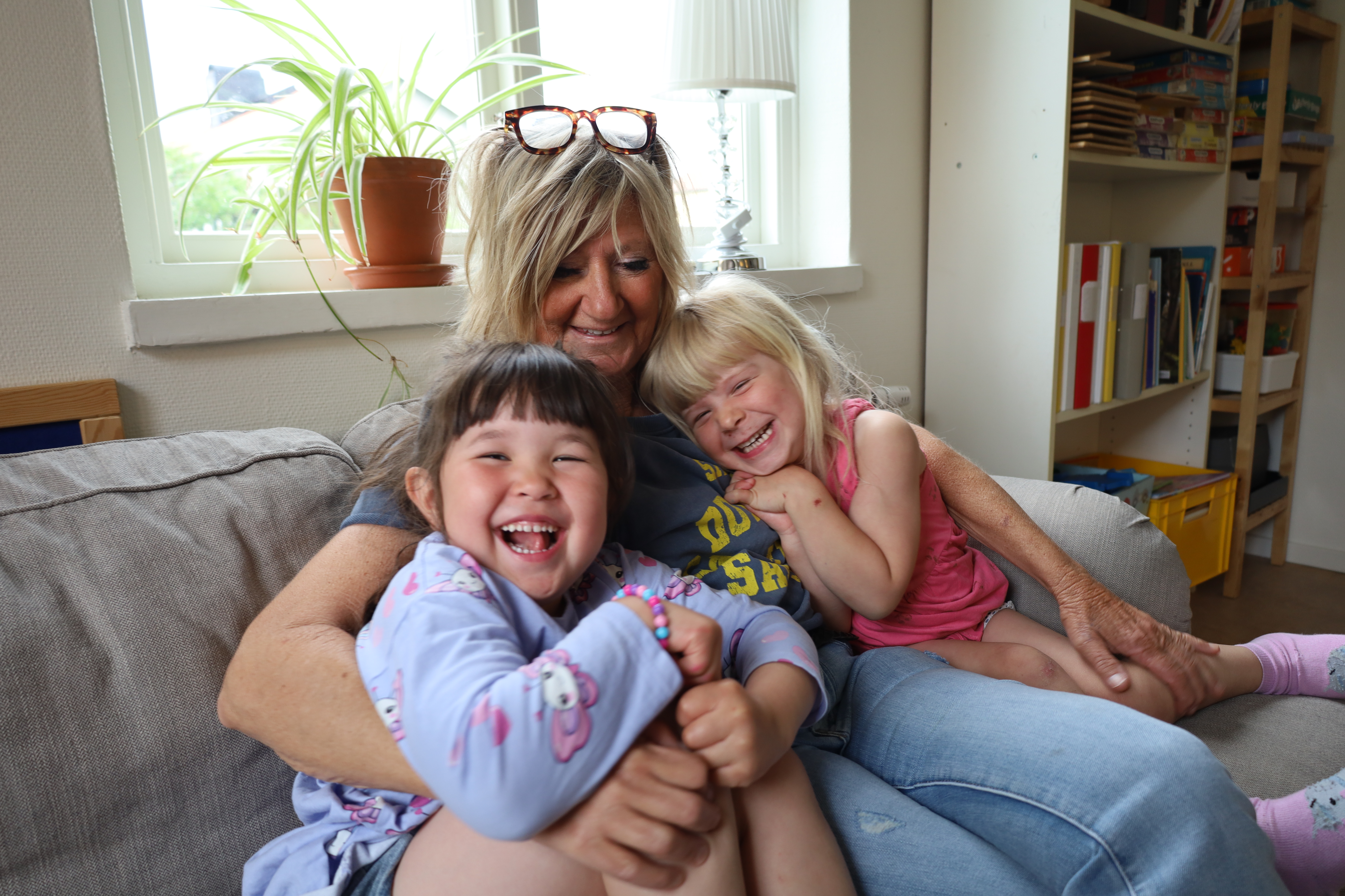 Dagbarnvårdaren Maria sitter i soffan tillsammans med två dagbarn.